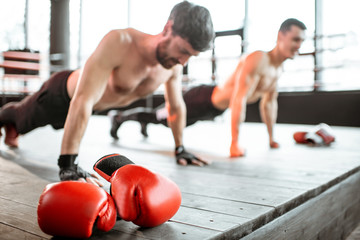 Two athletic men doing push-ups on the boxing ring, training before boxing at the gym