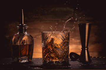 Whiskey on table with cocktails tools and splash