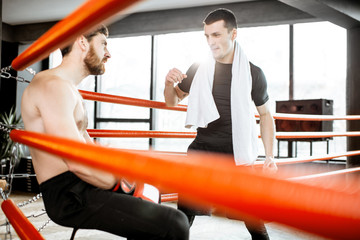 Boxing trainer giving instructions during a break motivating a boxer sitting on the corner of the...