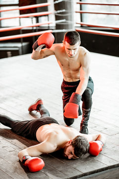 Beaten Boxer Lying Knocked Out On The Boxing Ring With Strong Man Winner Above