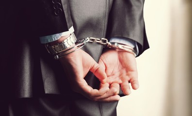 Cropped image of male hands in handcuffs behind his back