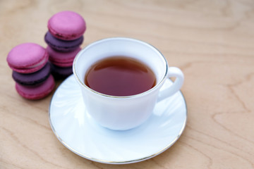 Cup of tea with saucer and macaroon on wooden background. Minimalism