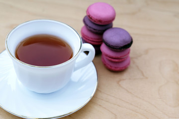 Cup of tea with saucer and macaroon on wooden background. Minimalism