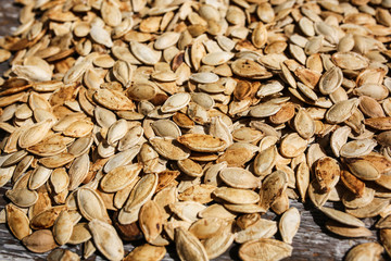Fried pumpkin seeds lying on the old rustic background. Vegetarian superfood. Healthy diet. Natural texture background.