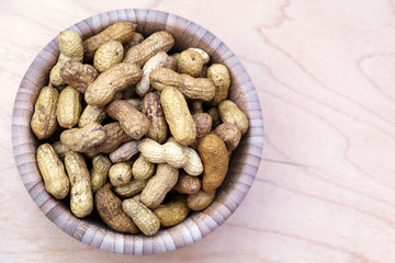 Peanuts in shell in a bowl on wooden background