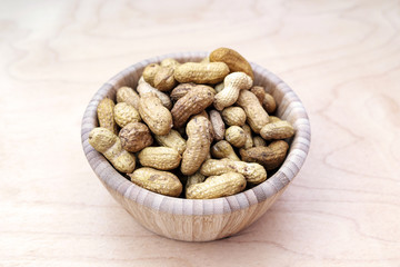 Peanuts in shell in a bowl on wooden background