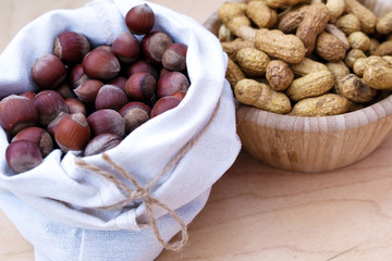 Hazelnuts and peanuts in the composition. Natural wood and linen bag.