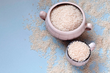 White uncooked rice in mug on blue background. Carbohydrates, healthy food. Place for text.