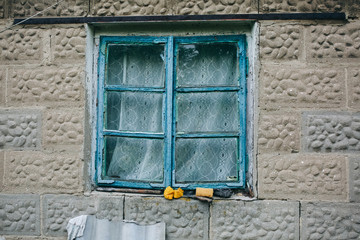 Old rustic window with blue dye in the village.
