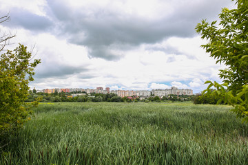 Beautiful view over the city. Post soviet buildings in the town. Green park with trees and field at...