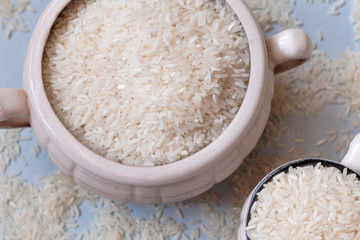 White uncooked rice in mug on blue background. Carbohydrates, healthy food. Place for text.