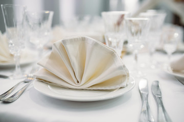 Luxury dinner set arranged on a table with vintage cream lace tablecloth and napkins, elegant porcelain dishes, silverware and crystal glassware