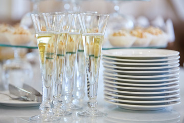 Catering services. Glasses with wine in row background at restaurant party. Clean plates and cutlery on white table 