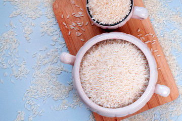 White uncooked rice in mug on blue background. Carbohydrates, healthy food. Place for text.