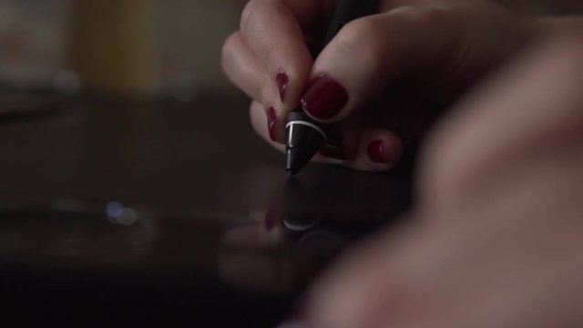 SLOW MOTION: Detail of drawing with digital pen in womans hand on graphic tablet