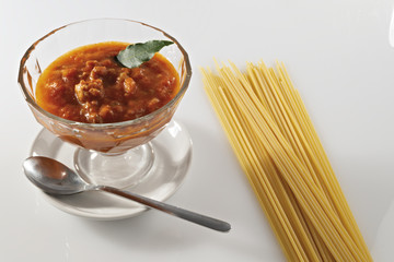 ragù di carne e pomodoro in ciotola di vetro e pasta cruda orizzontale da sopra