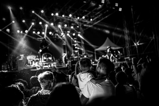 Young Boy And His Family Attending A Concert And Rising Hands In The Air. Black And White Effect Applied