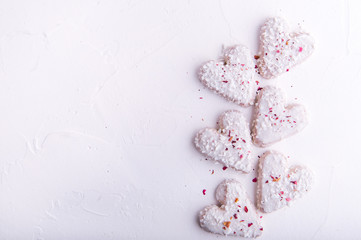 White heart shaped Valentine's day cookies with white glaze and coconut flakes. Copy space. Flat lay