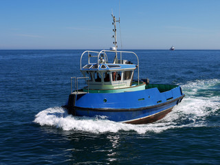 Harbour tugboat underway at speed to harbour facilities.