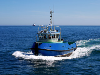 Harbour tugboat underway at speed to harbour facilities.
