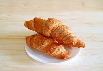 Plate of whole wheat croissant pastries served on wooden table with free space for text or design 