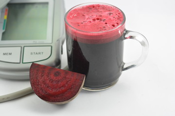 Beetroot juice with blood pressure machine on white background