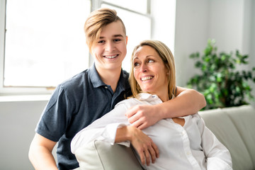 A people and family happy teen boy with mother on sofa at home