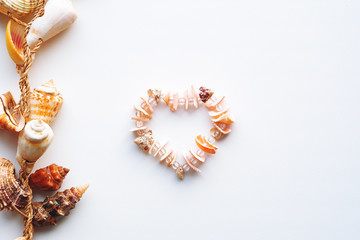 a necklace of pink shells in the shape of a heart.shell frame on white background.with copy space