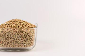 Natural fresh green buckwheat in glass bowl isolated on white background.