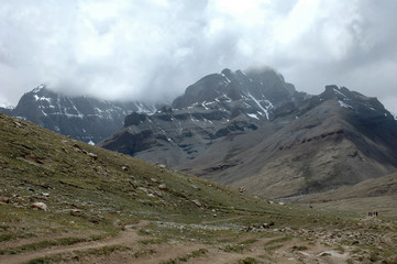 The green slope of the mountain on the way bypass the holy mount Kailash on background of gray...
