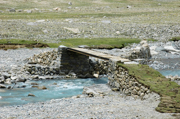Bridge over the river on the way sacred bypass mount Kailash on the background of gray clouds,...