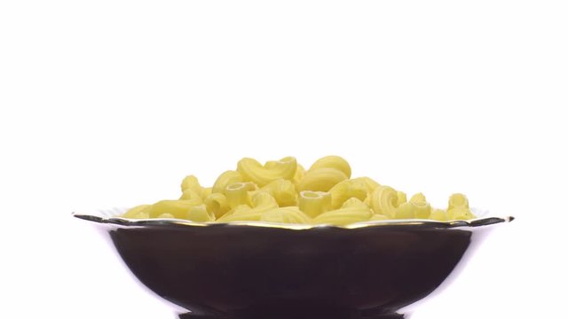 Raw macaroni in rotation. Elbow macaroni.  Macaroni rigati close up.  Raw pasta  isolated on white. Italian cuisine concept.