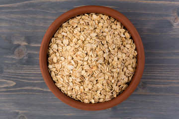 Rolled oats or oat flakes in bowl on wooden background. Healthy lifestyle, healthy eating concept. Top view