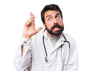 Young doctor with his fingers crossing on white background