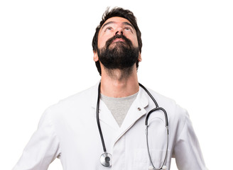 Young doctor looking up on white background