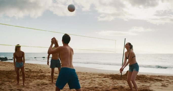 Active friends playing beach volleyball, slow motion volleyball rally