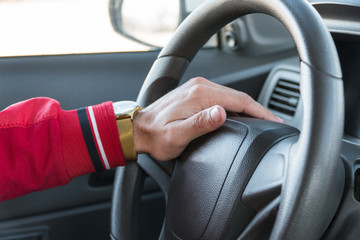 men's hand with a watch on the steering wheel of a modern car