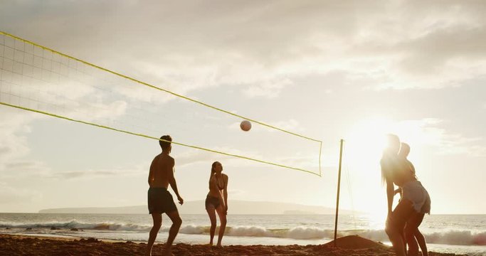Active friends playing beach volleyball at sunset, summer active lifestyle