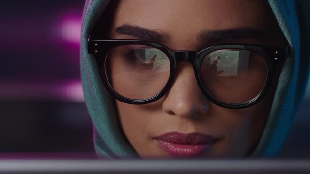 close up portrait beautiful muslim business woman using tablet computer working late browsing internet brainstorming looking at information on screen wearing glasses