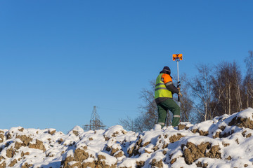 A surveyor's assistant with a measuring instrument conducts a topographical survey for cadastre
