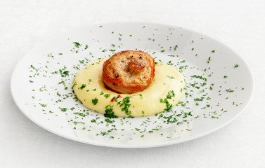 bacon wrapped spiralled rabbit loin on mashed potato decorated with parsley