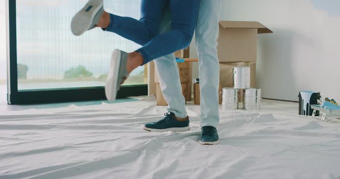 Happy husband spinning wife in his arms in new home, happy homeowners, home improvement