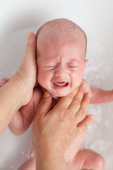 Fototapeta na wymiar Newborn baby is being bathed by his mother. Newborn baby crying in bath time
