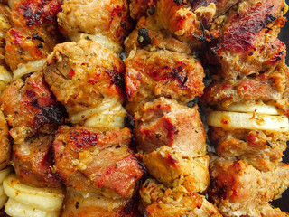 Shish kebab frying. Meat dish preparing open air on charcoal with onion, spices & herbs. Food background