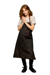 A full-length shot of a Young redhead woman with apron scheming something over isolated white...