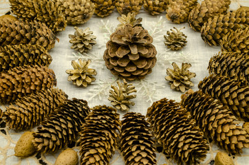Embroidered white wavy napkin with a pattern of cones of different breeds, snowflakes and almonds along the edges of the pattern on a black background

