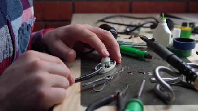 Crop hands of master putting wire on switcher in workshop