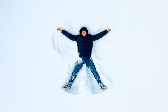 The boy on a snow flapping arms and legs angel shows.