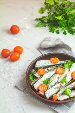 Sardines with tomatoes slices and spaces on ceramic plate