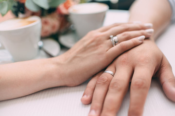 The bride and groom hold hands, holding expensive wedding rings with white gold, on the background...